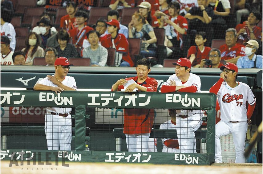 <div class="caption"> マツダ スタジアムのベンチでデータを確認する白濱スコアラー</div>